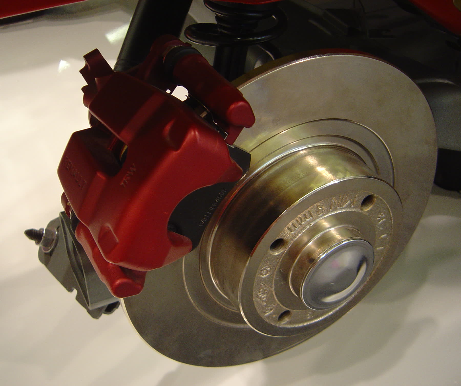 A red brake caliper and drilled disc on a display stand
