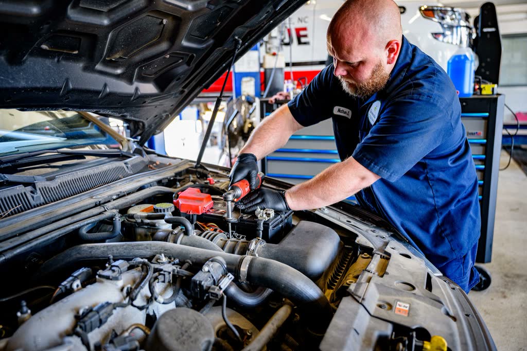 A technician working on an engine with the bonnet open